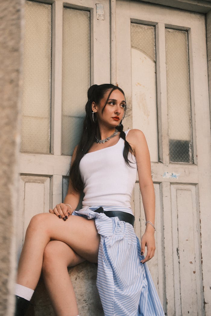 Trendy young woman in casual attire posing confidently by a vintage door.